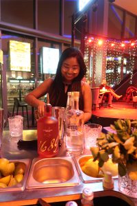 Een jonge dame achter een tafel vol cocktail spullen